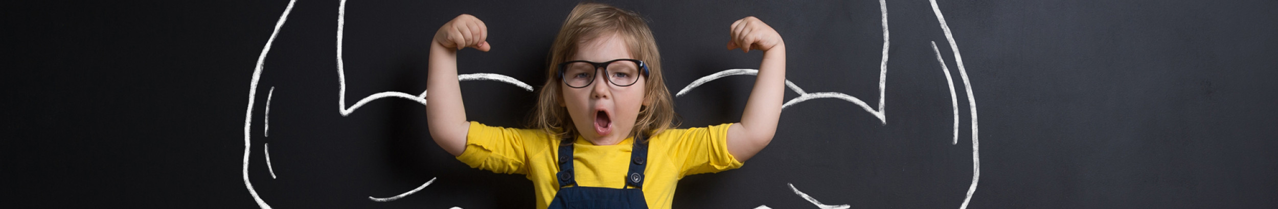 Child with muscled arms drawN on blackboard behind child